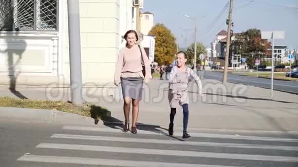 一位年轻女子带着一个10岁的女儿在一个行人过路处过马路视频的预览图