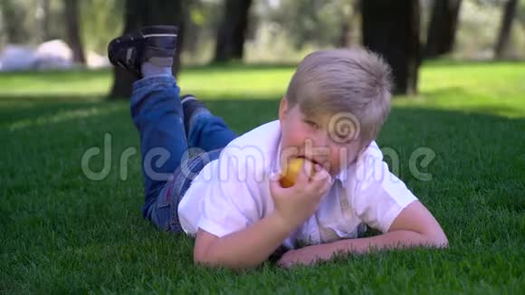一个孩子躺在草坪上吃苹果视频的预览图