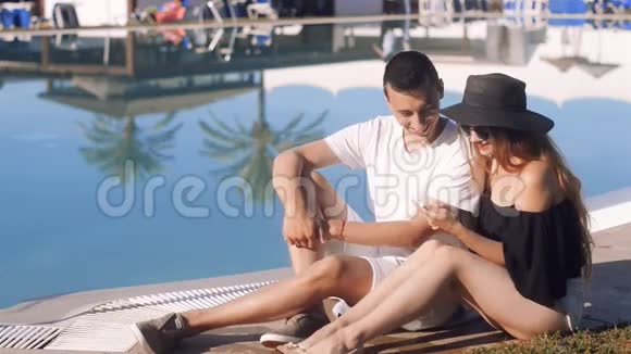 在游泳池附近休息的无忧无虑的恋人戴太阳镜戴帽子的女孩度假日光浴放松假期旅游视频的预览图