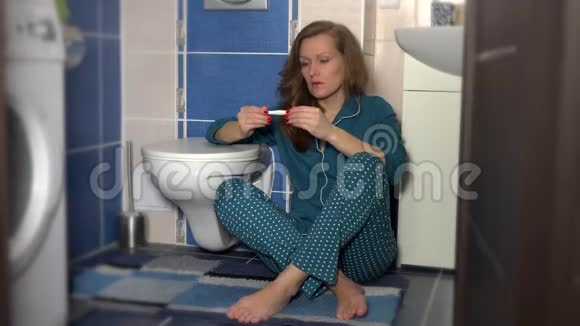 沮丧的女人坐在浴室地板上拿着阴性的妊娠试验视频的预览图