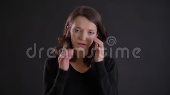 年轻迷人的白种人长发女孩在黑色背景下做按摩的肖像视频的预览图