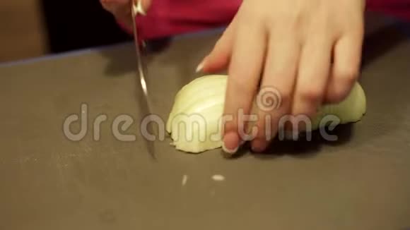 家庭主妇把洋葱切成两半厨师用洋葱做蔬菜沙拉把洋葱加到盘子里视频的预览图
