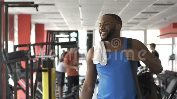 肌肉发达的非裔美国人脸上带着微笑走在健身房里遇见朋友视频的预览图