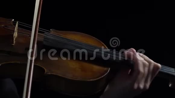 女人在黑暗的房间里拉小提琴弦黑色背景闭合视频的预览图