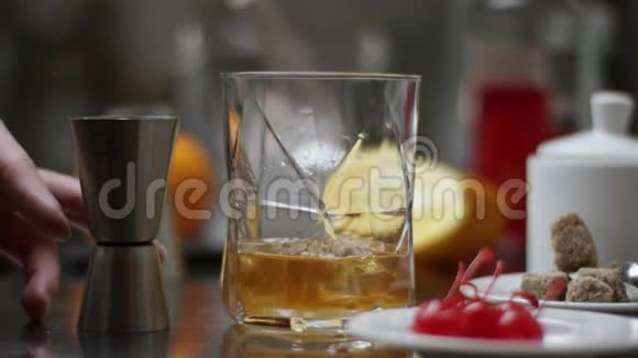 酒吧老板把威士忌倒在杯子里木桌上放冰块黑黑的背景重点放在冰块上威士忌上视频的预览图
