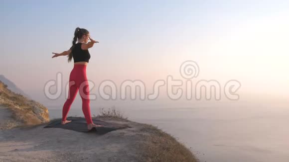 美丽的景色女人做瑜伽伸展在山上日落时的海景把手举起来视频的预览图