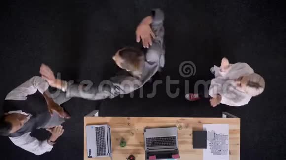 三个穆蒂族的工人正在桌子旁跳舞手提电脑和眼镜办公室里有香槟公司聚会视频的预览图