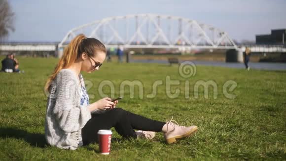女孩在手机上说话年轻迷人的女人坐在草地上打电话有魅力的女性视频的预览图