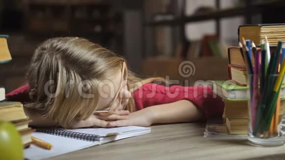 在家里睡在书桌前的一个金发女孩视频的预览图