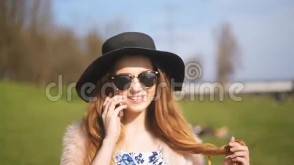 一个戴着黑色帽子和太阳镜的漂亮女孩在街上打电话旅行中的女孩打电话来开心而微笑视频的预览图