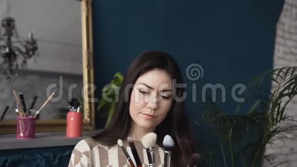 一位年轻的女化妆师在一家美容院拿着化妆刷一套化妆刷在女人手中在一个视频的预览图