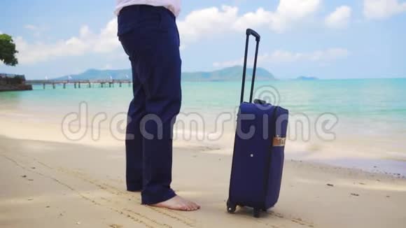 穿西装的商人带着一个手提箱沿着美丽的大海的海岸散步自由职业概念期待已久的休闲视频的预览图