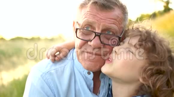 一个卷曲的小学生和他的祖父的特写肖像那个人高兴地拥抱了他的孙子家庭假期快乐视频的预览图