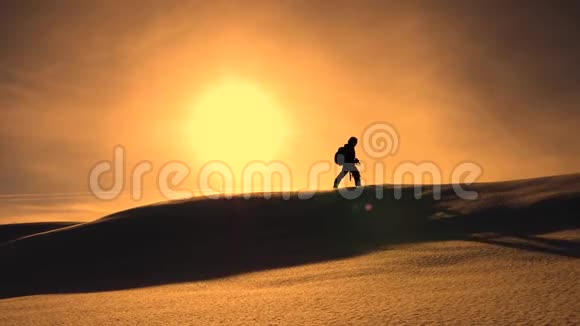 冬天的摄影师在黄色的日落中登上雪岭带相机和三角架的登山者视频的预览图
