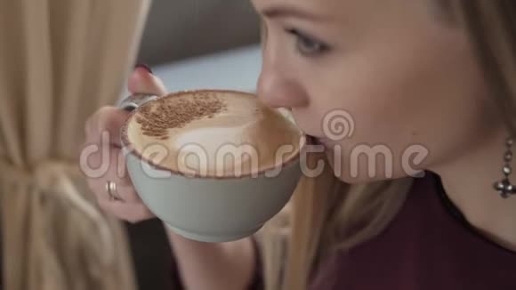 可爱的女人带着一杯调味咖啡坐在咖啡店里视频的预览图