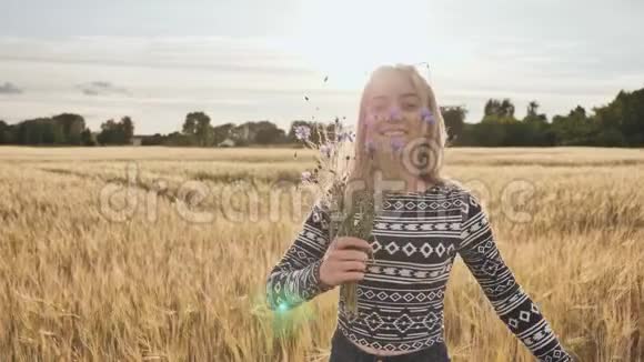 一个16岁的少女开着矢车菊的花在一片田野里旋转视频的预览图