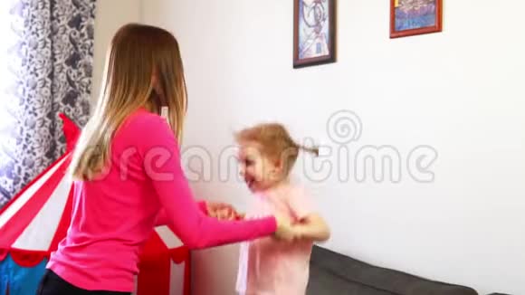 一个小女孩在沙发上跳着慢动作地牵着妹妹手视频的预览图