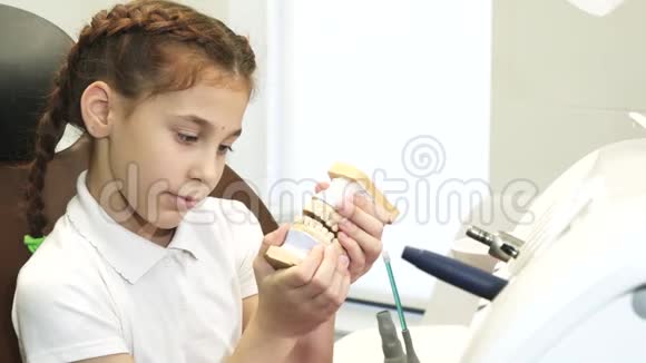 一个好奇的女孩在牙医办公室里被人用假牙颌玩耍视频的预览图