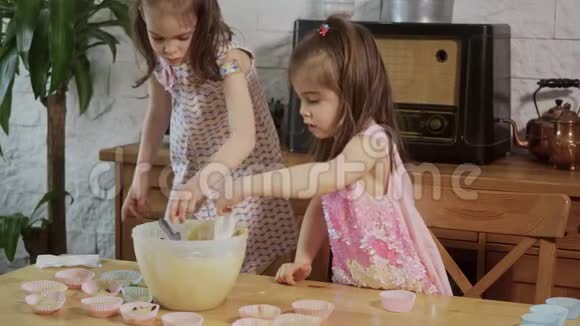两个小女孩把奶油放在模具上做纸杯蛋糕视频的预览图