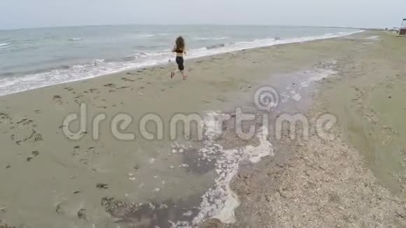 苗条的女人沿着空滩奔跑训练和欣赏风景空中射击视频的预览图