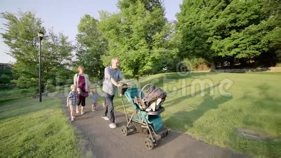 幸福的年轻家庭在外面的道路上行走绿色慢动作全高清视频的预览图