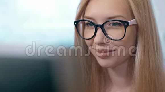 戴眼镜的年轻女人在电脑上工作视频的预览图