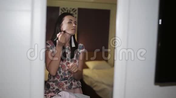 一个中年妇女站在酒店的走廊里在出去之前做了一些化妆视频的预览图