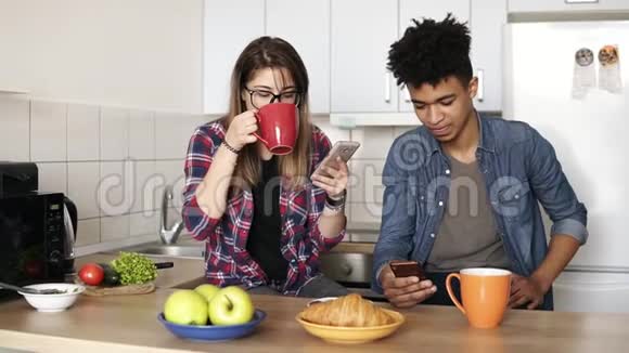 可爱的一对夫妇在家里的厨房里一起吃早餐漂亮的白种人女孩和她的穆拉托男友视频的预览图