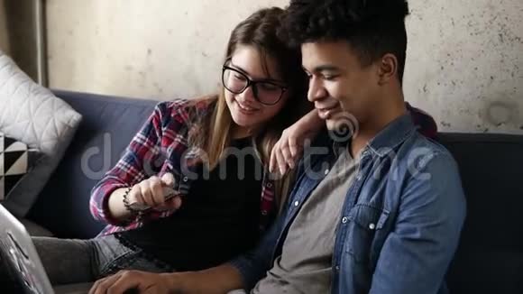 可爱的幸福夫妇坐在沙发上用笔记本电脑视频的预览图