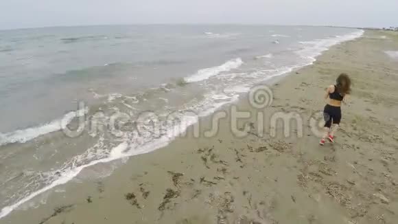 不错的女孩在海滩上跑步在海滨训练空中射击视频的预览图