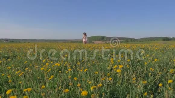 穿着漂亮的女人穿着黄色的花和扬起的手臂在田野里奔跑视频的预览图