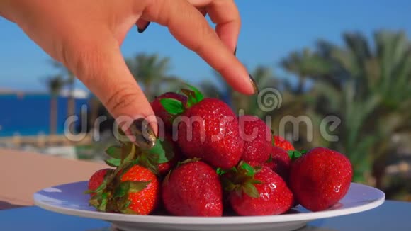 手从盘子里取出一大块多汁的草莓视频的预览图