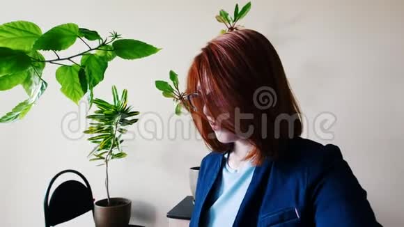 办公室里的女工在笔记本电脑上打字桌子上放着植物视频的预览图