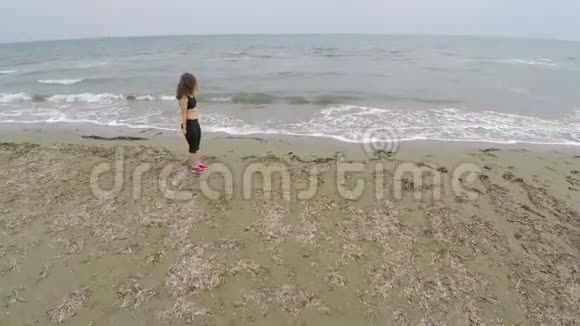 布鲁内特女运动员在沙滩上训练做蹲运动和健康视频的预览图