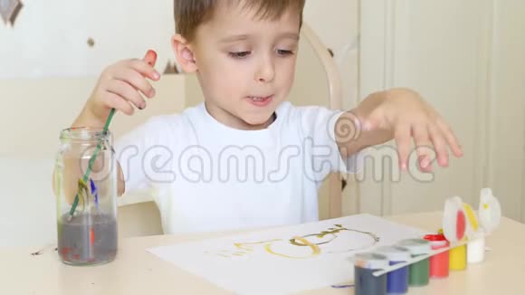 一个小男孩在一张白纸上画图纸上面画着水粉颜料特写镜头视频的预览图