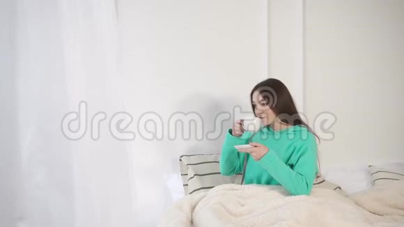 一个年轻的女人最近醒过来从杯子里喝热咖啡视频的预览图
