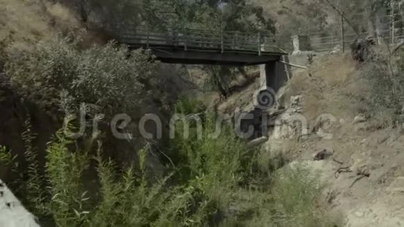 沿着森林中央一座废弃的桥下的一条小溪视频的预览图