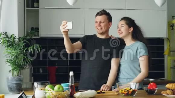 小幸福夫妇在家厨房做饭时用智能手机摄像头在线视频通话视频的预览图