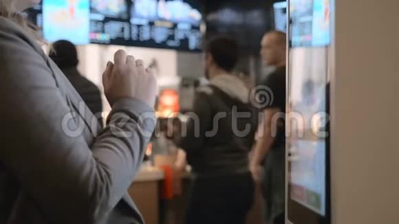 女士选择食品通过自助机在快餐店使用自助触摸终端的人视频的预览图