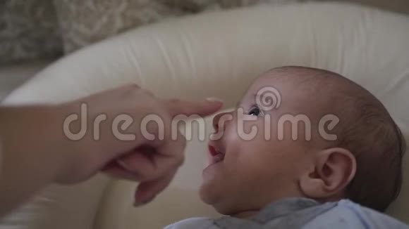 快关门母亲抚摸躺在婴儿床小儿子的鼻子迷人的婴儿微笑小男孩视频的预览图