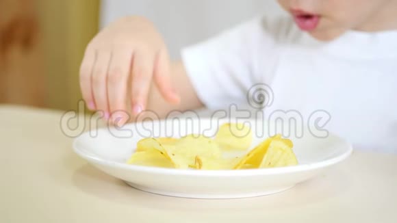一个小男孩把手中的薯片从一个白色的盘子里拿出来特写视频的预览图