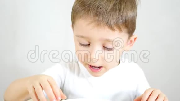 一个小男孩高兴地吃着白色盘子里的薯片特写镜头视频的预览图