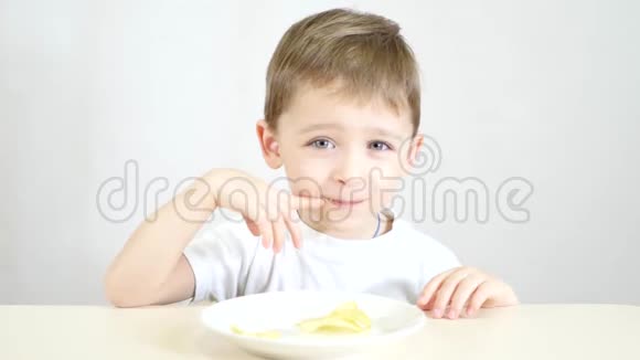 一个小男孩高兴地吃着白色盘子里的薯片视频的预览图