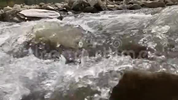 快山河的水在一块大石头周围流动产生泡沫飞溅气泡和大量水滴视频的预览图