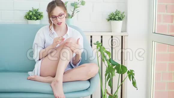 人们美容化妆品身体护理和水疗的概念美丽的女人在家里的腿上涂润肤霜视频的预览图