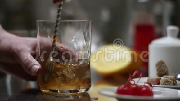 经典波旁鸡尾酒酒保把威士忌倒在玻璃杯里木桌上放着冰块黑黑的视频的预览图