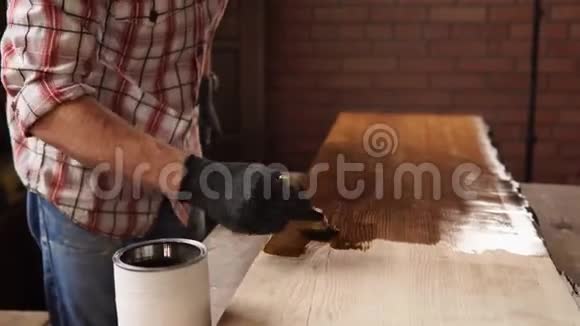 木工在小作坊里用棕色油漆木头视频的预览图