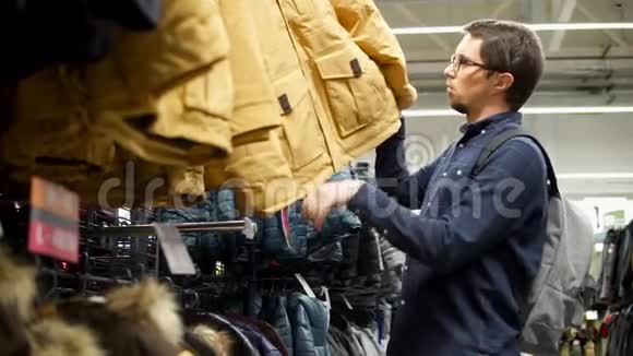 一个成年人选择一件冬季夹克衣服在购物中心的货架上视频的预览图