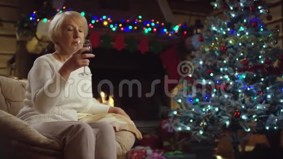 老妇人在圣诞树旁喝酒视频的预览图