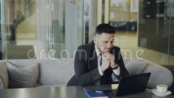 考虑周到的白种人商人坐着思考他的商业计划同时看着他的笔记本电脑屏幕视频的预览图